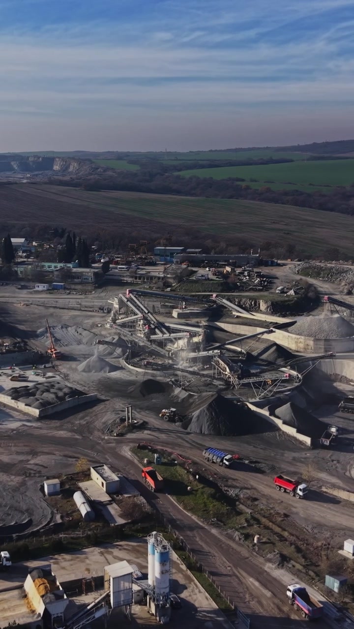 Quarry site with machinery and piles of materials in a rural area