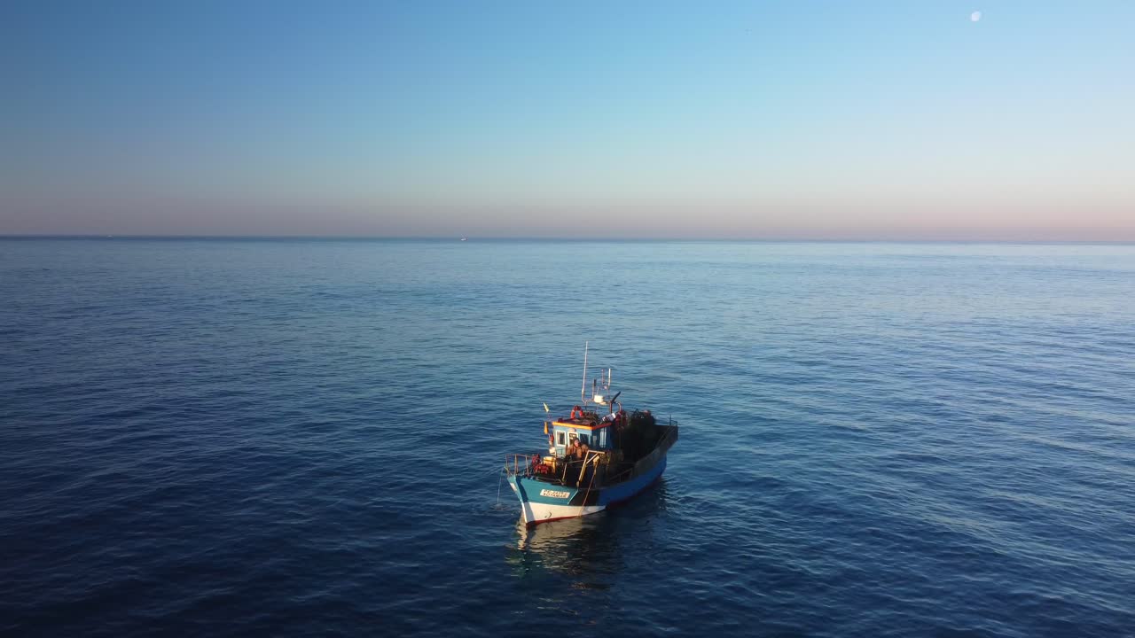Peschereccio con grande pescato, stormo di gabbiani in volo, vista aerea da drone al tramonto invernale