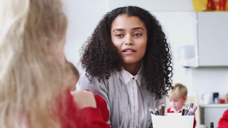 Joven-Profesora-Sentada-En-Una-Clase-De-Escuela-Infantil-Hablando-Con-Niños,-De-Cerca