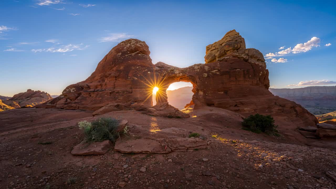 Sol se alinhando, criando um efeito de estrela e depois deslizando por trás de um arco de rocha vermelha em uma mesa desértica, iluminando a rocha.