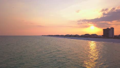 Eine-Drohne,-Die-Bei-Sonnenuntergang-Rückwärts-über-Einen-Wunderschönen-Strand-Fliegt