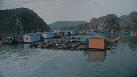 Sailing-Past-Floating-Fishing-Village-Among-Beautiful-Limestone-rocks-of-Lan-Ha-bay,-the-southern-edge-of-Ha-Long-bay