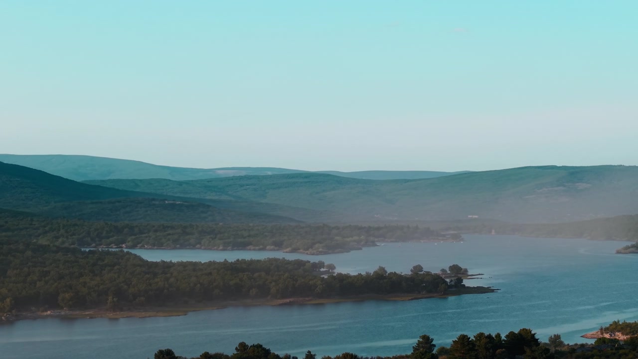 Panoramautsikt over en rolig innsjø omgitt av frodige grønne åser