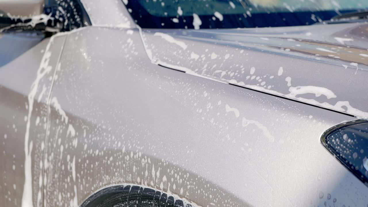 Primo piano di shampoo per auto che impregna un SUV grigio