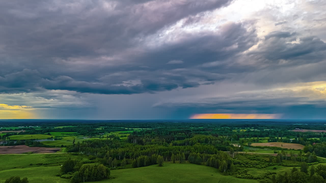 Rain and clouds roll through the idyllic European, rural countryside landscape in this high altitude aerial time lapse at dusk