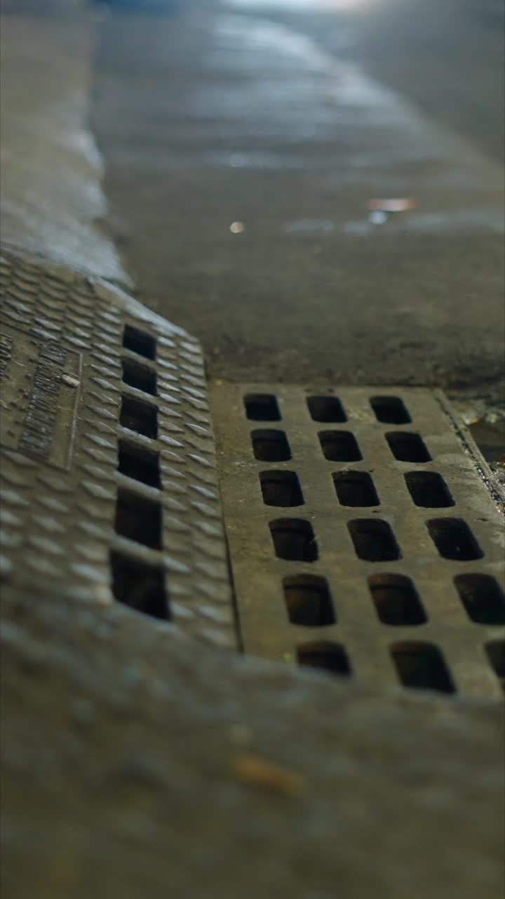 Grille d’égout sur une rue mouillée de nuit