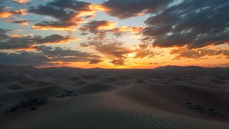 a desert landscape with a beautiful sunset in the background. the sky is filled with clouds, and the sun is setting, casting a warm glow over the sand dunes. the scene is serene and peaceful