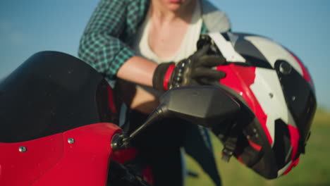 un primer plano del espejo delantero de una motocicleta roja cuando una mujer pone su casco, preparándose para un paseo