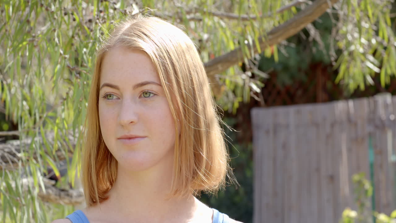 Standing outdoors in garden, woman looking away thoughtfully