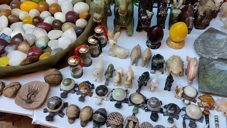 various stone figures and animals for sale on a tablecloth