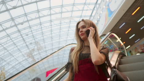 Young-smiling-woman-in-blue-t-shirt-standing-in-shopping-center-using-smartphone,-browsing,-reading-news,-chatting-with-friends