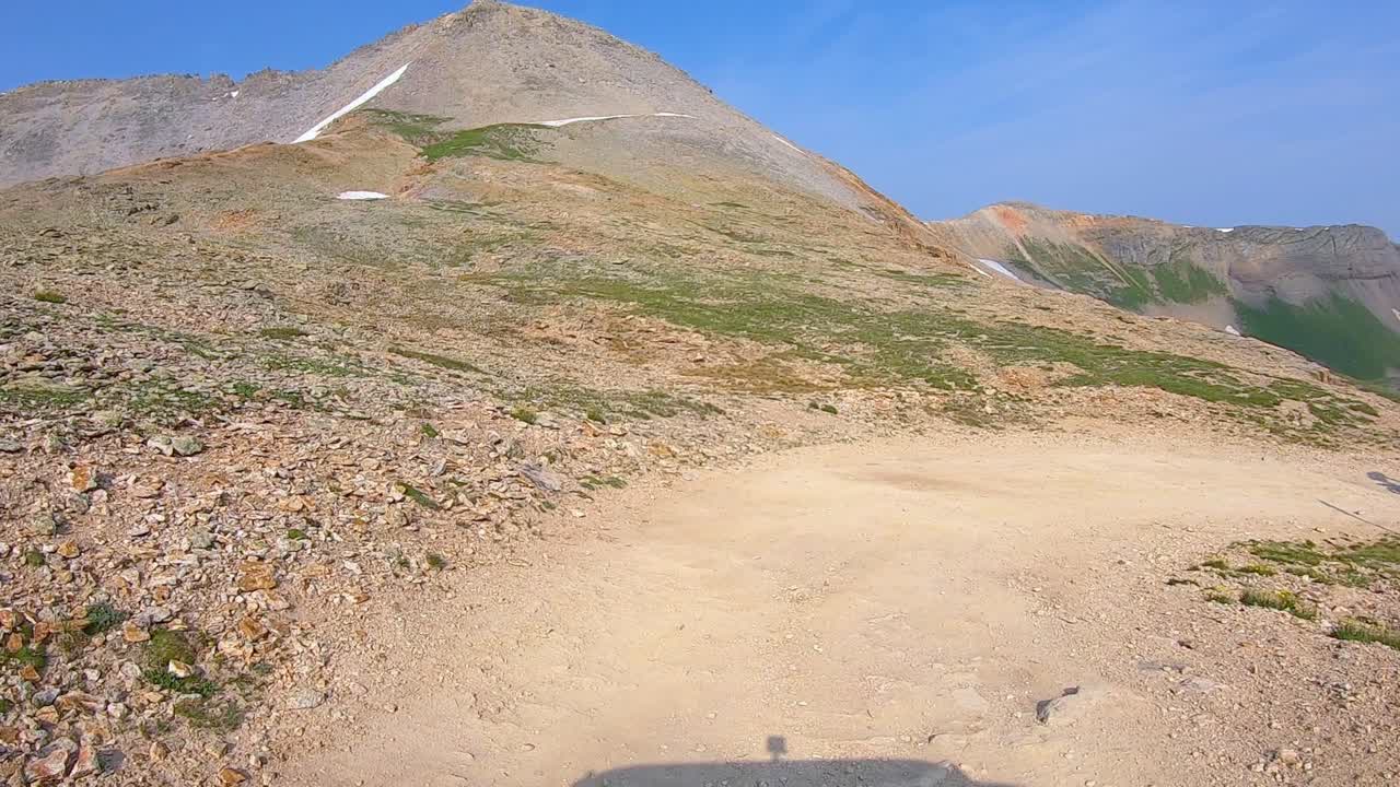 POV di guida sul sentiero fuoristrada del Black Bear Pass mentre una moto da cross supera il veicolo su una curva a tornante nelle montagne di San Juan vicino a Telluride, Colorado: concetti di avventura e scarica di adrenalina