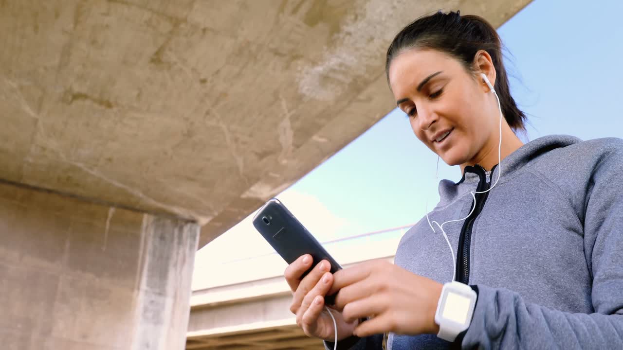 mujer escuchando música en el teléfono móvil mientras corre 4k