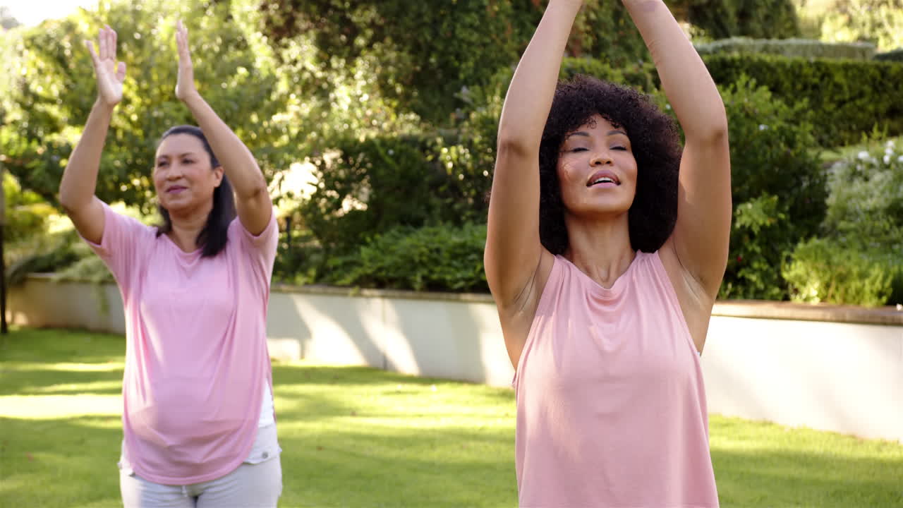 Practicing yoga outdoors, women in pink tops meditating in garden