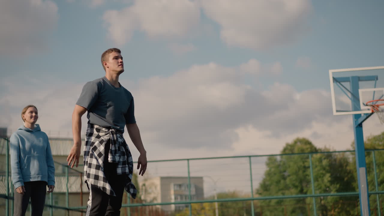 sesión de entrenamiento de voleibol con un individuo que se prepara para servir mientras otros miran en el fondo, actividades deportivas que ocurren en el trasfondo, capturando la dinámica del equipo y la atmósfera deportiva