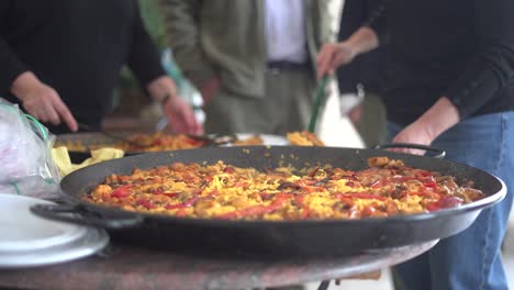 serving paella to a gathering of people celebrating