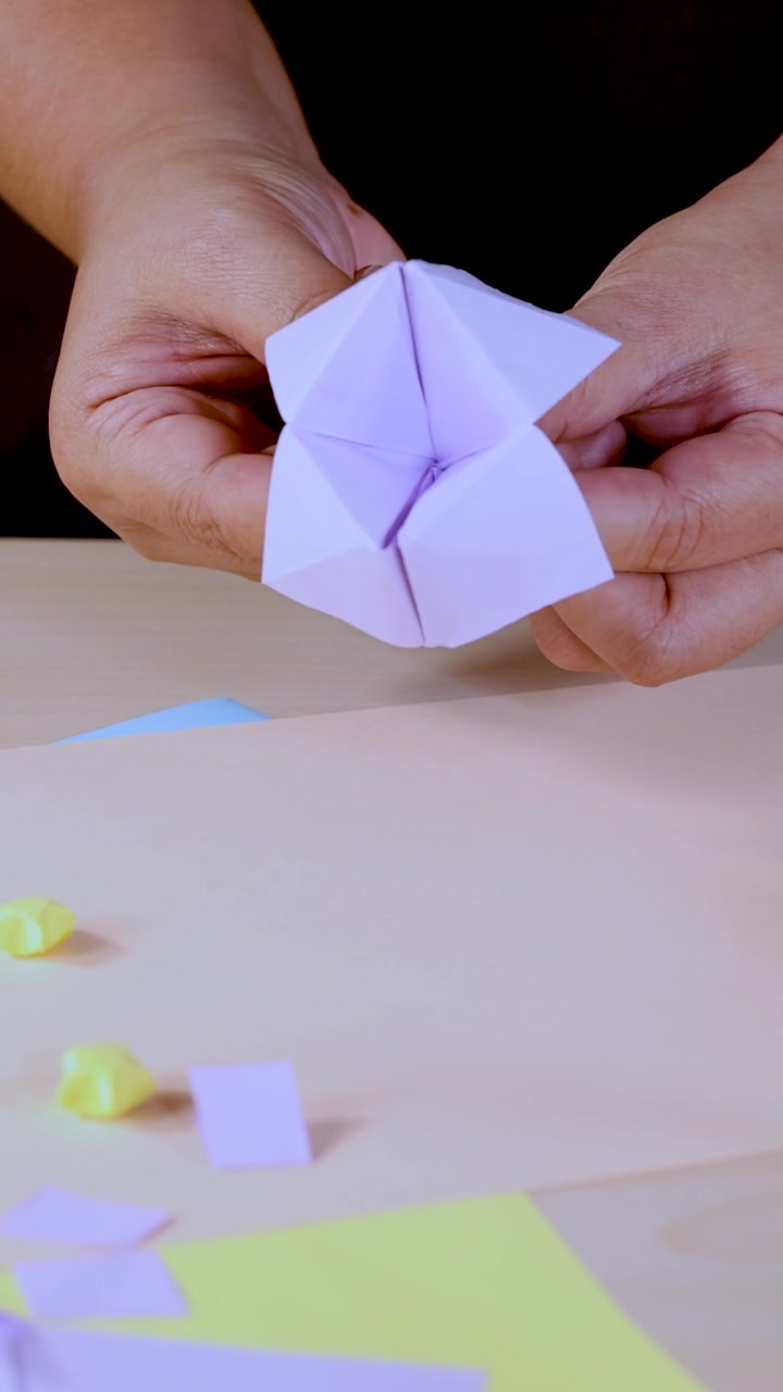 Mani che giocano con un indovino di carta viola.