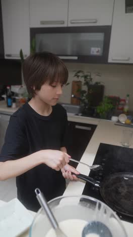 boy cooking pancakes in the kitchen