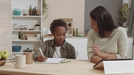 mother helping son with homework in kitchen