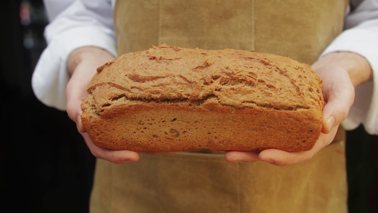 The baker holds in hands a of fresh bread close-up. Artisan bread is making by skill bakers using natural and high-quality ingredients. Food with health and flavour benefits.