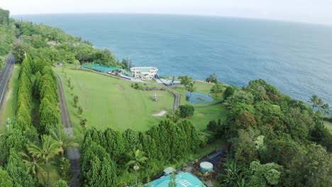 top-down aerial view of a chopper parked in the middle of the lawn next to a luxurious villa surrounded by lush green foliage