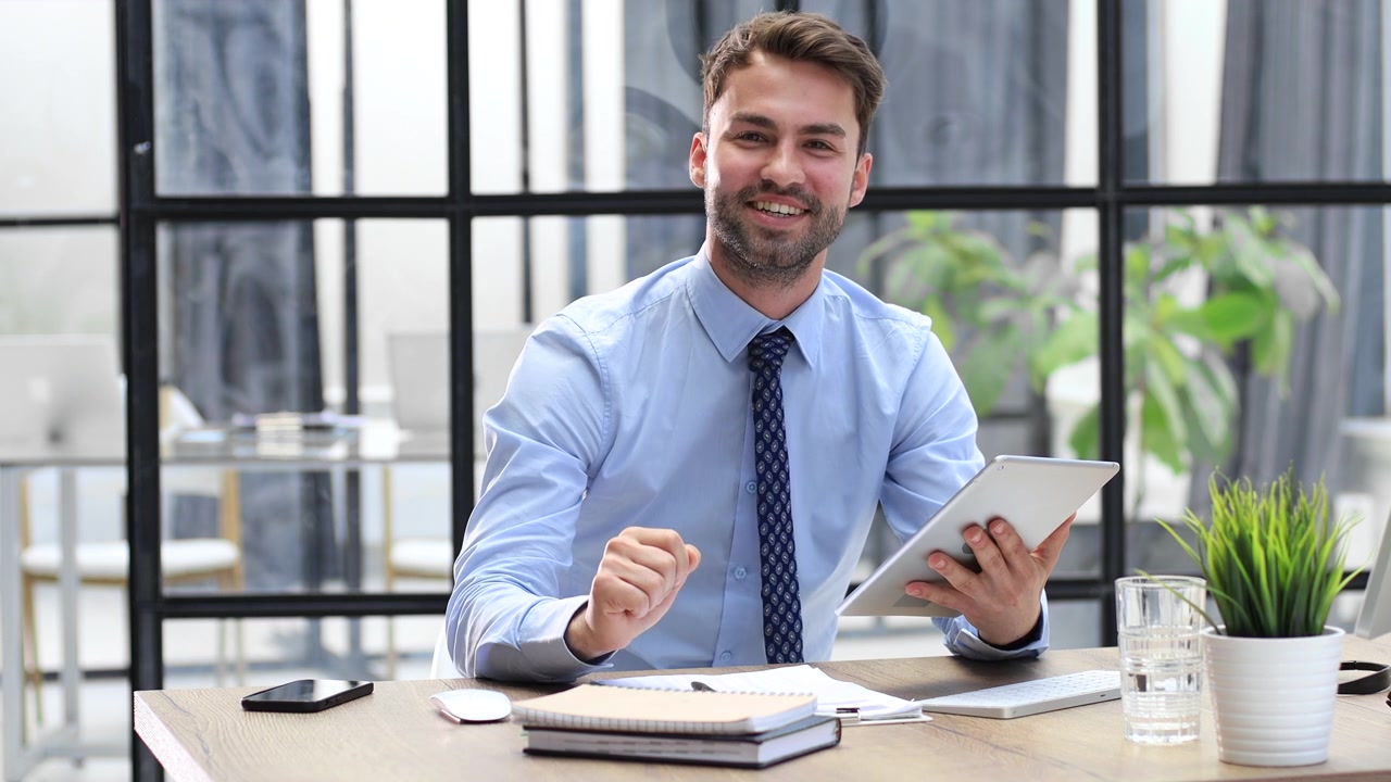 Uomo d'affari professionista che parla e gesticola con il tablet in ufficio