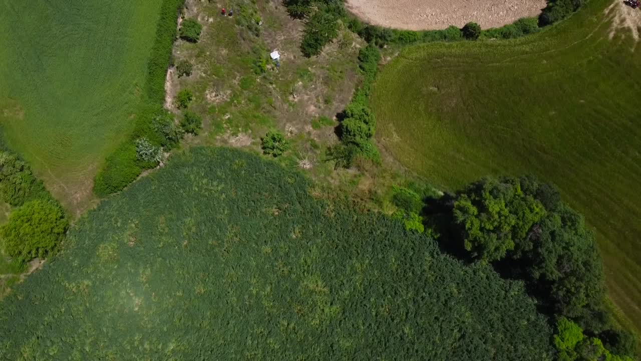 vista de drones de una ciudad rodeada de campos de trigo verde, con montañas en el fondo y un cielo azul