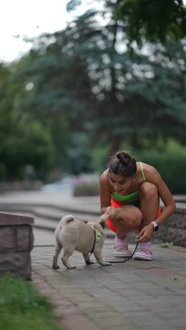 mujer jugando con un pug en un parque