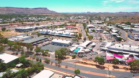alice springs - australia. cinematic aerial flyover of outback city with pan up to reveal red rock desert beyond. filmed on dji mavic pro