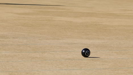 a player skillfully rolls a ball on a sunny lawn bowls green, capturing the sport's precision and focus