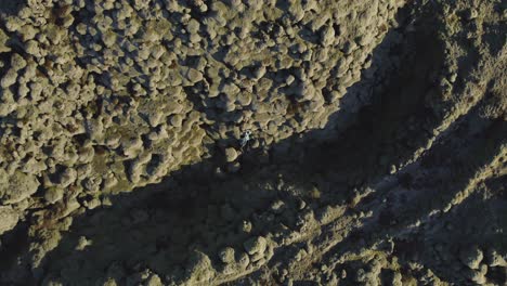 vista aérea de arriba hacia abajo de una pareja acostada en un campo de lava en islandia