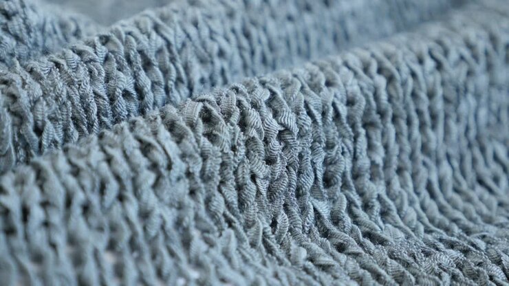 Filmato UltraHD 4K 2160p 30fps con lenta inclinazione sui dettagli della texture di un maglione lavorato a maglia con profondità di campo ridotta - Primo piano di una texture fine di maglieria verde, video UHD 3840x2160 con inclinazione.