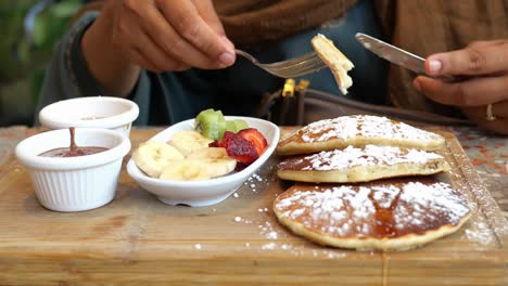 woman enjoying a delicious breakfast of pancakes with fruit and chocolate sauce