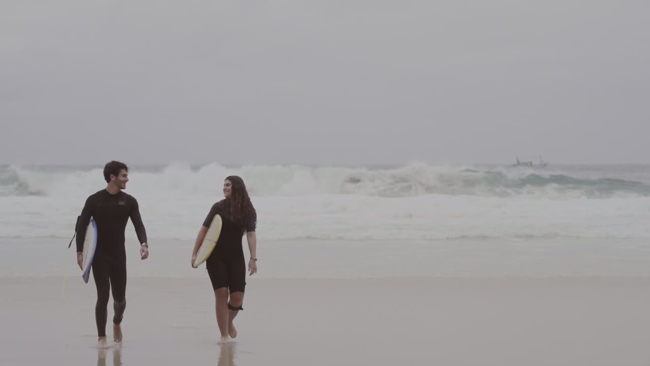 Two Surfers Walking Along a Beach