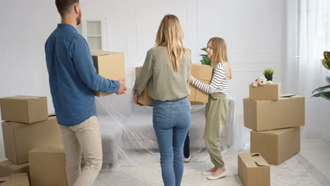 caucasian happy family with kids carrying carton boxes in new home