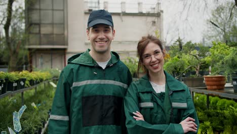 green-thumbed gardeners: smiling professionals posing among plants and flowers in specialized shop