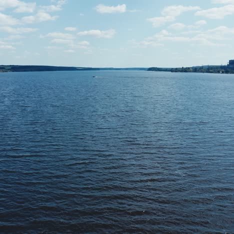 quick motion camera over the blue river. natural water background. industrial factory near the river. beautiful lake under the blue sky.