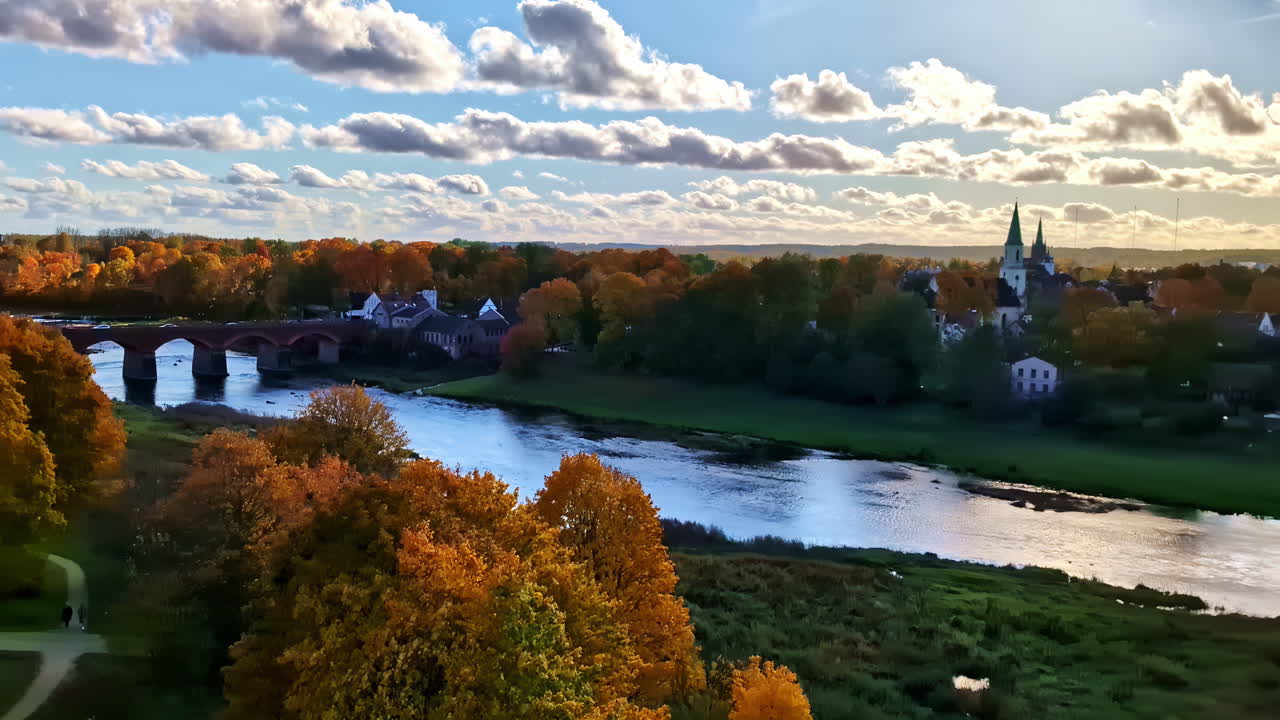 Aerial footage of Kuldiga with the Venta River, church towers, and colorful autumn trees. Kuldiga, Latvia