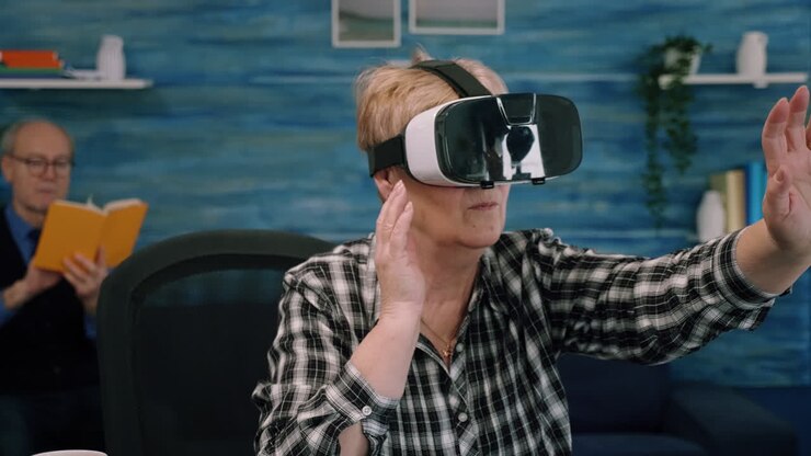 Anziana donna in pensione concentrata che usa occhiali per la realtà virtuale in salotto