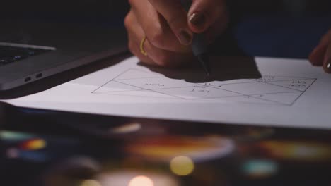 close up of woman using laptop to draw astrology lagna or birth chart on candlelit table 3