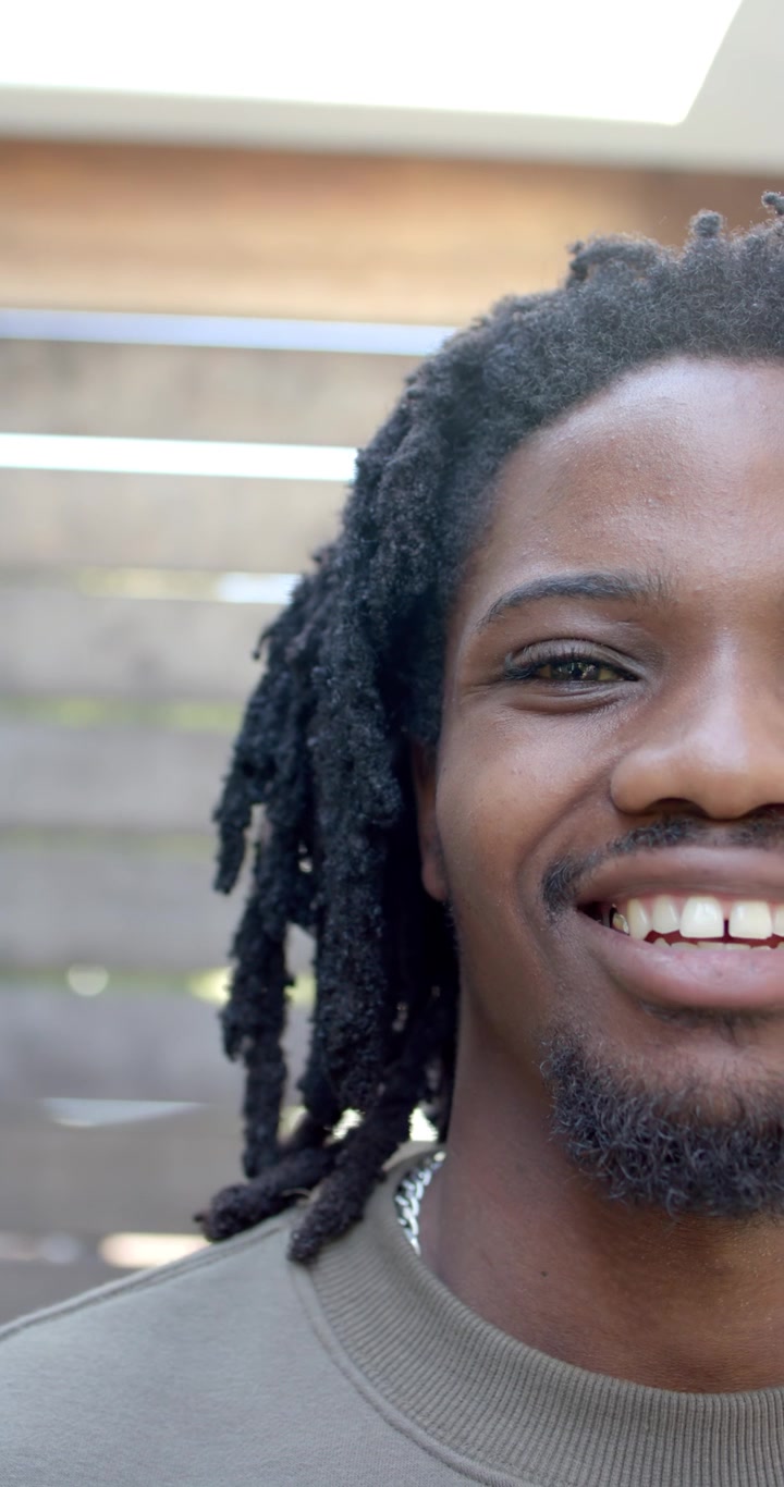 Video verticale: Uomo adulto che apre gli occhi dopo una pausa, sorridendo, ridendo in un patio e indossando una catena.