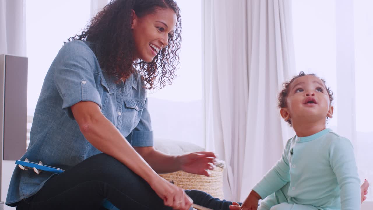 joven madre negra tocando el xilófono con su hijo pequeño