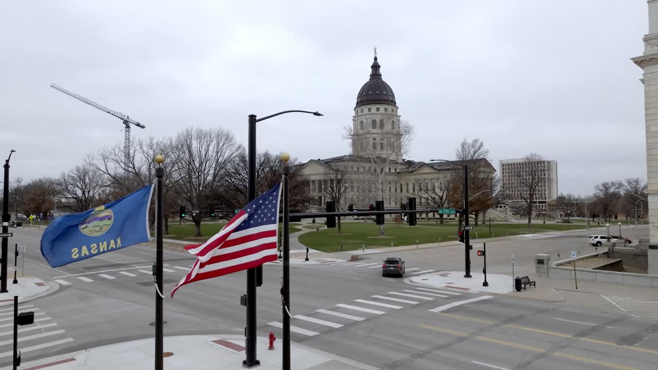 Kansas' delstatsparlamentsbygning med flag, der blafrer i vinden i Topeka, Kansas, med dronevideo, der bevæger sig opad.