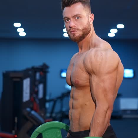 muscular athlete doing exercise with barbell. strong man working out arm muscles. bodybuilding shoulder exercise in a gym.