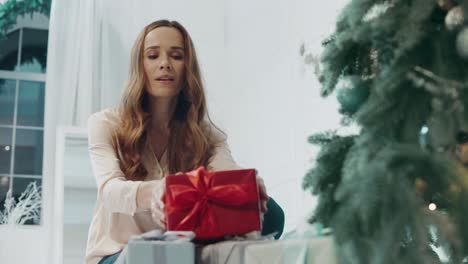 retrato de una mujer feliz saliendo presente en un apartamento decorado de año nuevo.