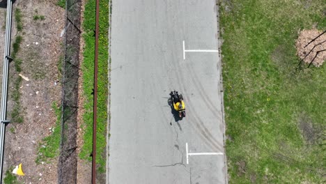 una vista de arriba hacia abajo de un hombre en una bicicleta reclinada, montando en un parque vacío en un día soleado