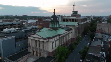 aerial approaching shot of lancaster county courthouse with cupola and clock. dusk scene in downtown of city. houses and apartments in small town of america