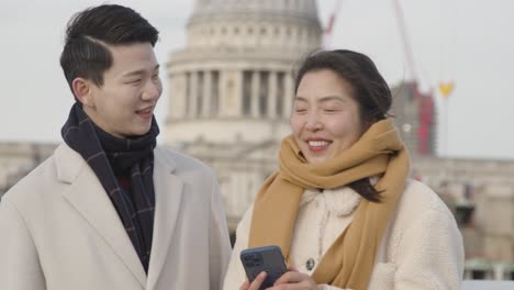 배경 3에서 세인트 폴 대성당과 밀레니엄 다리를 건너 휴일에 젊은 아시아 부부