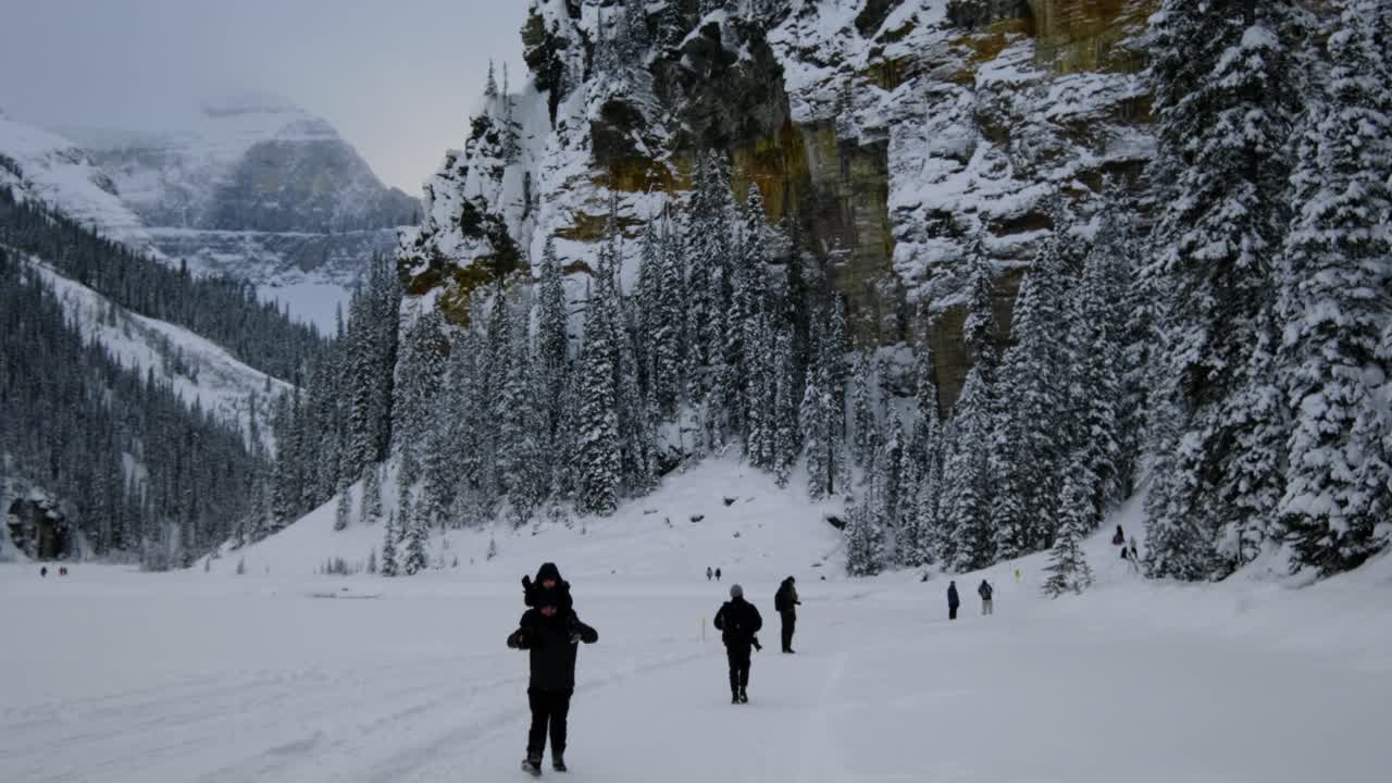 People enjoying a snowy adventure on Lake Louise in Canada during winter - tilt up