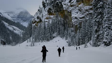 people enjoying a snowy adventure on lake louise in canada during winter - tilt up